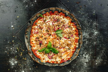 A top view of appetizing pizza with black dough and various vegetables