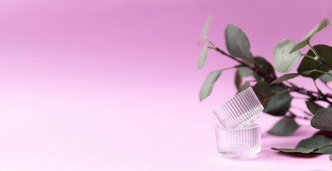 
glass jars and a branch of eucalyptus on a pink background. fashion background