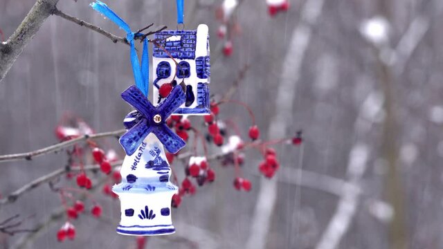 Blue ceramic Christmas toy bought in Amsterdam hangs on a branch