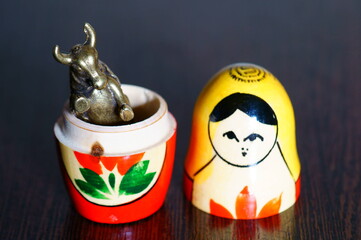 A metal bull and a figure of a matryoshka doll on the table.