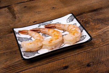 Shrimp on porcelain plate and dark wooden table