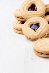 Top view of a group of heart-shaped cookies with strawberry jam, on white table, in vertical, with copy space