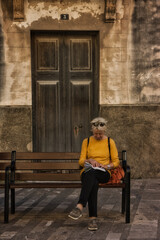 Obraz na płótnie Canvas old woman reading a book on the street