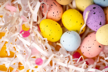 Easter composition with colored eggs lying in a nest of paper on a yellow background. Beautiful background and space for text