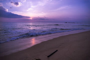 Fioletowo różowe niebo, krajobraz zachodzącego słońca na tle tropikalnej plaży i oceanu.