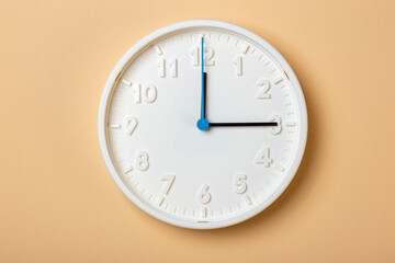 white wall clock with blue second hand show three o'clock