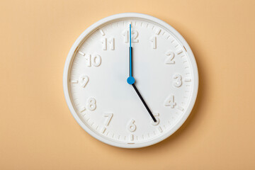 white wall clock with blue second hand show five o'clock