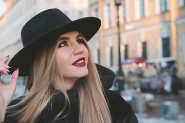 white beautiful blonde woman in black hat on the street