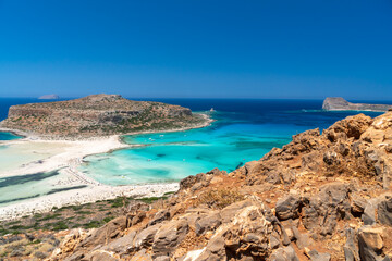 Fototapeta na wymiar Amazing Panoramic view of Balos Lagoon near Chania, with magical turquoise waters, lagoons, tropical beaches of pure white, pink sand and Gramvousa island on Crete, Cap tigani in the center . Greece