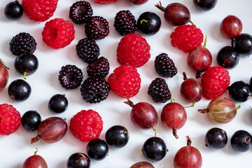 Fresh berries of raspberries, currants and gooseberries on a white background, assorted berries
