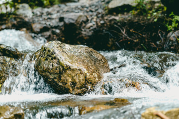 Close up of rapid clean stream flowing on rocks. Mountain river flows down and splashes.