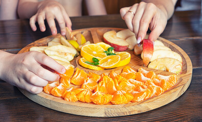 Hands take fruit from a wooden plate. 