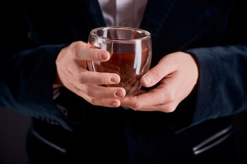 Tea master holding a glass cup of freshly brewed herbal tea