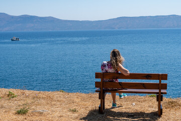 Naklejka na ściany i meble Woman sitting on a bench in front of the sea. Balos near to Chania. Grece