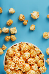 Caramel of the popcon in a white cup with a scissor on a blue background.