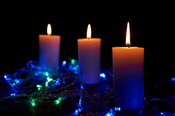 Obraz na płótnie Canvas Flame candles with decorative lights on black table background 