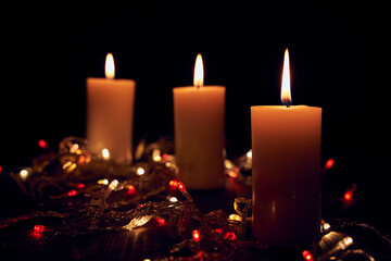 Obraz na płótnie Canvas Flame candles with decorative lights on black table background 