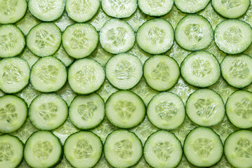 Fresh green slices of cucumber as background.