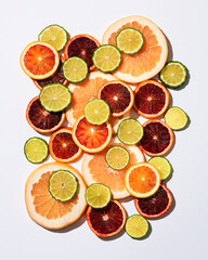 An arrangement of lime slices, orange slices, and grapefruit slices on a grey background