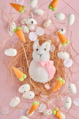 Flying quail eggs and White Rabbit in nest and sweet carrot on pink background. Easter minimal creative vertical composition with copy space. Spring Happy Easter holiday Greeting card. Top view.