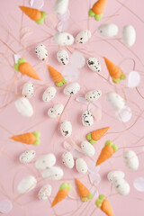 Flying quail eggs in nest and sweet carrot on pink background. Easter minimal creative vertical composition with copy space. Spring Happy Easter holiday Greeting card. Top view.