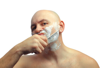 A Caucasian man tries to shave with a knife. A brutal bald man holds a knife in his hand and shaves his stubble. Close-up of a face in shaving foam.