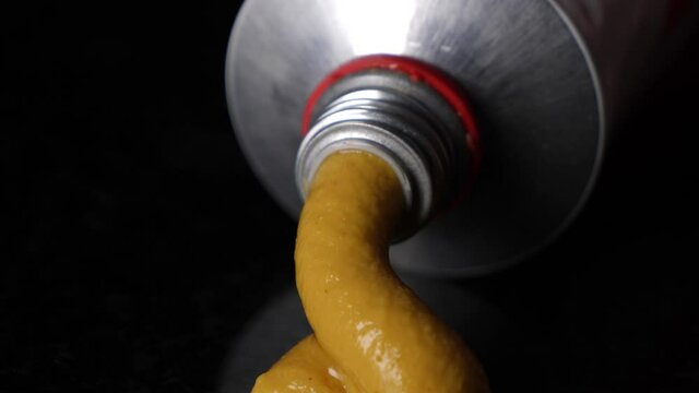 Extreme close up pressing mustard out of a tube, concept of jerking off