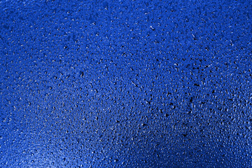 Small drops of water or condensation on a rich blue surface. Abstract background for a screen saver or backdrop. A flat, empty surface. Top view