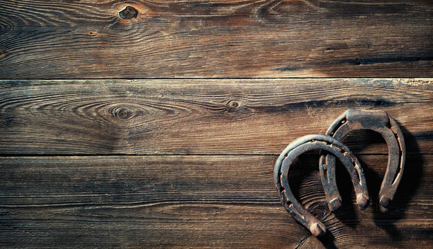 Two old rusty horse shoes on a rustic wooden