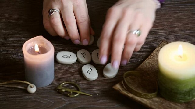 Hand holding rune stones, self-prophecy concept. Candles burning, home indoors.