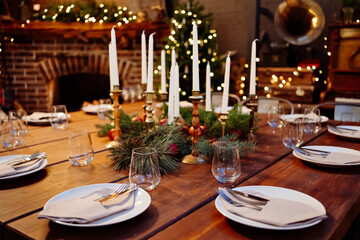 large square wooden table served for Christmas dinner. retro styled. Low light.