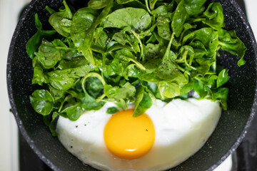 Fried eggs in pan with watercress, easy and healthy meal. Top view. 