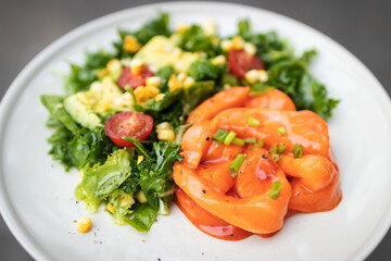 Fresh salmon toss spicy gochujang sauce with healthy green salad kale, corn and tomato on plate. 