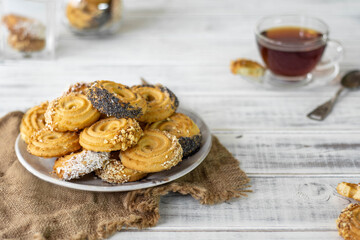 A plate with sackcloth cookies. Glass cup of tea on a saucer. White wood background