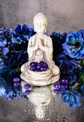 praying buddha statue with purple jelly beans and blue flowers
