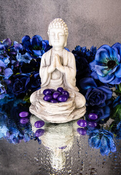 Praying Buddha Statue With Purple Jelly Beans And Blue Flowers