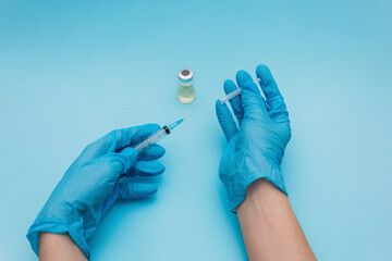 hands in blue gloves fill a syringe with a test tube of vaccine for vaccinations. the concept of...