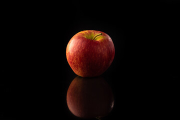 Apple, a beautiful red apple on reflective surface, black background, selective focus.