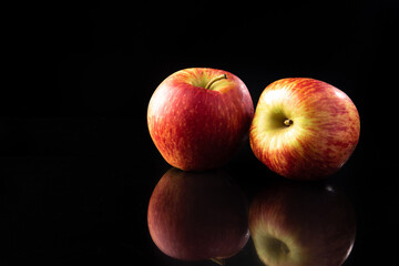Fototapeta na wymiar Apples, beautiful red apples on reflective surface, black background, selective focus.