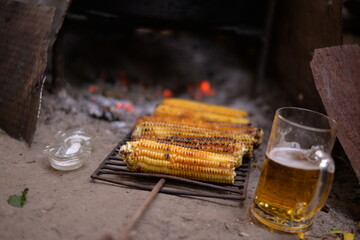 baked corn on the fire with a pint of beer next to it