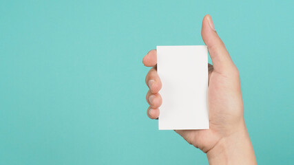 Male hand holding white blank card isolated on green or Tiffany Blue background.Empty space for text.