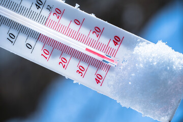 The thermometer lies on the snow in winter showing a negative temperature. Meteorological...