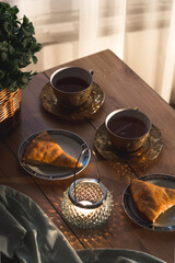 A cozy image of tea time. Flat lay of teacups, sweet pie, and candle. Cozy tea party concept