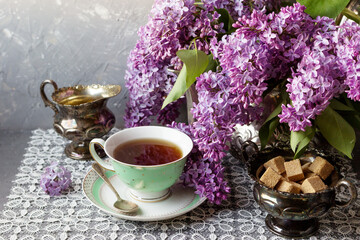 Obraz na płótnie Canvas Cup of tea with lilac flowers . Spring time. Vase with lilac. Selective focus.