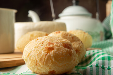 Cheese bread, Brazilian breakfast arrangement, cheese bread, white cheese, kettle and accessories, green towel, dark abstract background, selective focus.