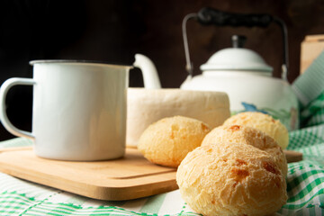 Cheese bread, Brazilian breakfast arrangement, cheese bread, white cheese, kettle and accessories, green towel, dark abstract background, selective focus.