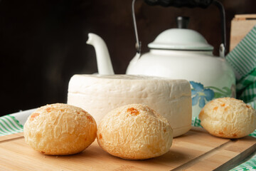 Cheese bread, Brazilian breakfast arrangement, cheese bread, white cheese, kettle and accessories, green towel, dark abstract background, selective focus.