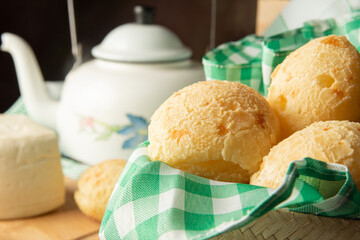 Cheese bread, Brazilian breakfast arrangement, cheese bread, white cheese, kettle and accessories, green towel, dark abstract background, selective focus.