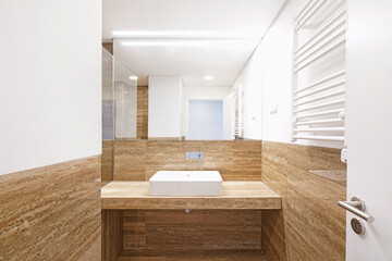 Modern bathroom, covered in stone on the walls, brown 