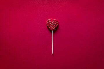 Heart shape red lollipop on the red background. Valentine's day greeting card